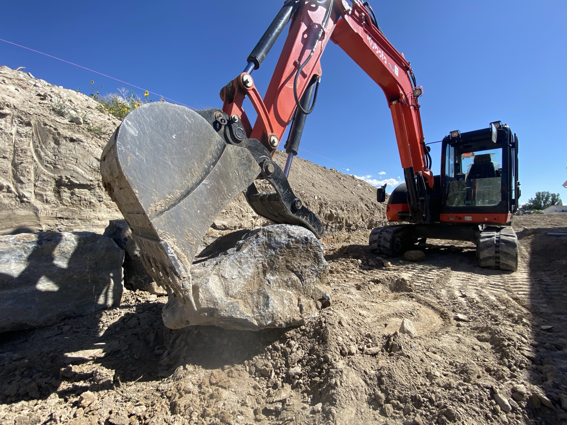 Excavator working on rocky terrain under blue sky